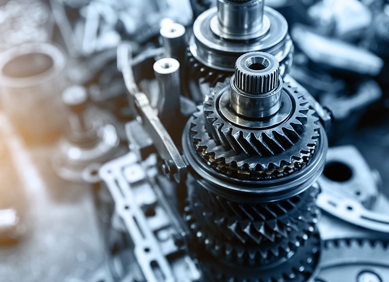 Close-up of shiny interlocking metal gears and other complex machine parts.